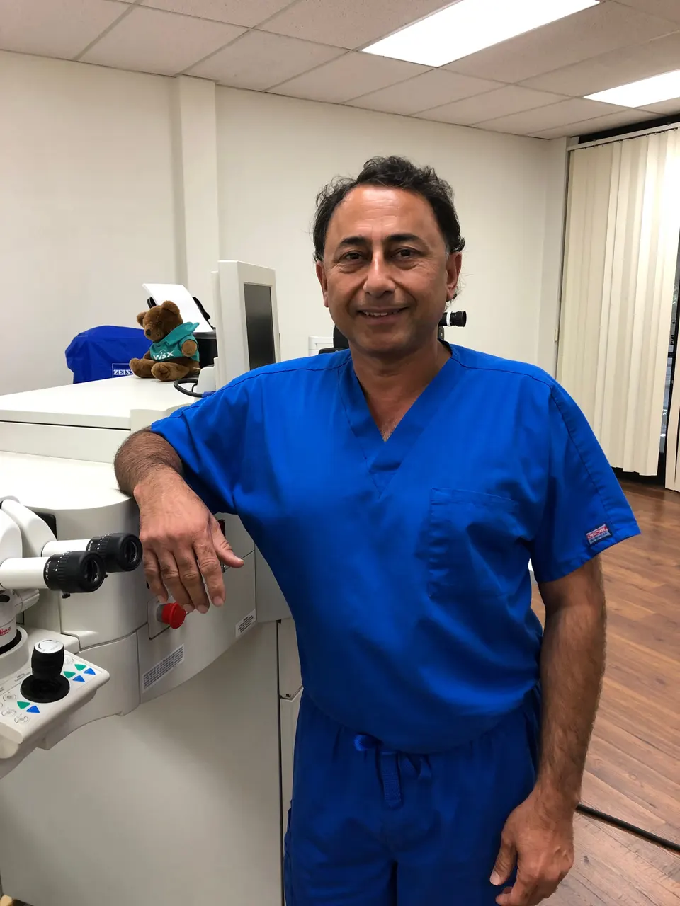 Rajesh Khanna, MD in blue scrubs in an exam room